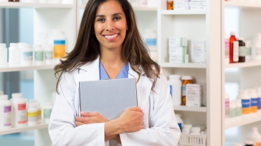 Pharmacist smiling and holding a clipboard.